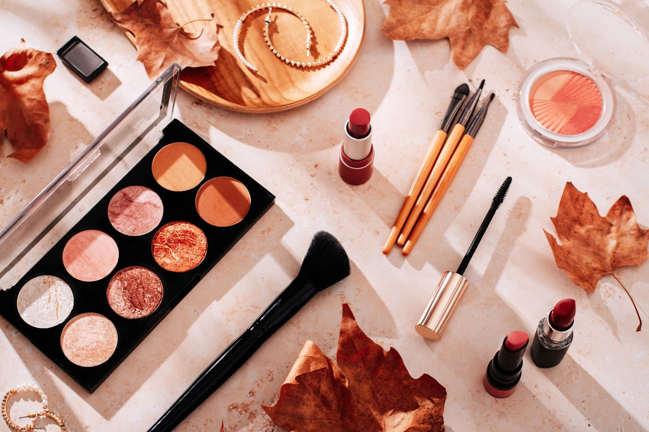Beauty products and makeup, autumn leaves on beige